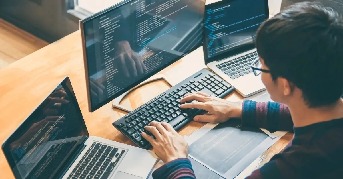 Professional freelance web developer writing code on multiple screens while building a modern website