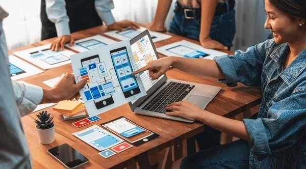 Mobile development team designing and reviewing mobile app interface layouts and user experience